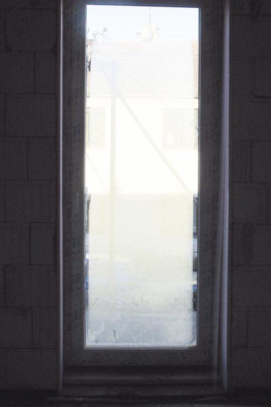 Balkónové dvere z interiérovej strany v novostavbe s vysokou vlhkosťou, október 2015 ráno. Orosenie je zjavné z obidvoch strán. Na vnútornej strane sa zasklenie (trojsklo) rosí pozdĺž krídla, na vonkajšej strane sú miesta priľahlé k rámu a pod nadpražím je naopak suchá a zarosená centrálna oblasť. V miestnosti, ktorá má bežnú relatívnu vlhkosť cca 50% by vnútorné rosenie nenastalo.
