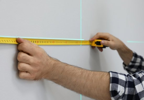 Krížový laser dokáže premietnuť vodorovnú aj zvislú čiaru, čo oceníte pri montáži políc, obkladov alebo sadrokartónových priečok. Zdroj: New Africa, Shutterstock