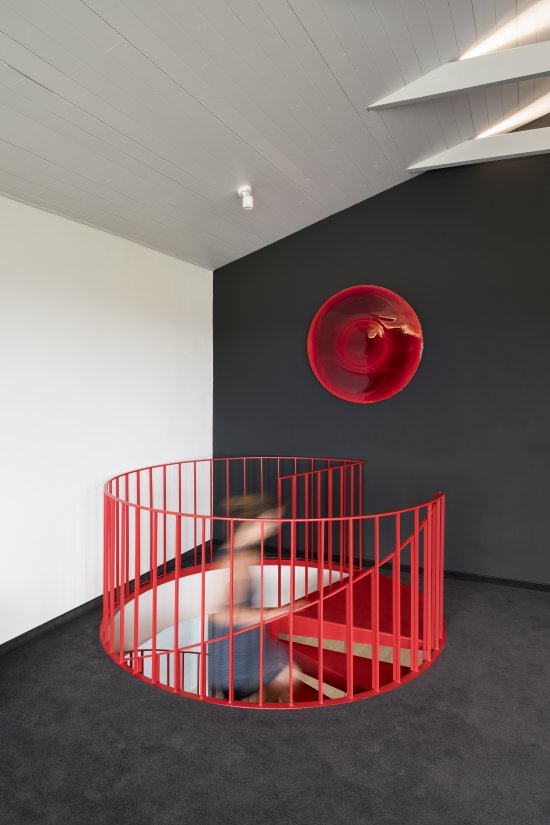 Abstraktné umelecké dielo zavesené nad schodiskom pochádza z dielne Milana Housera. Dopĺňa schodisko a koberec v rovnakej farbe. 