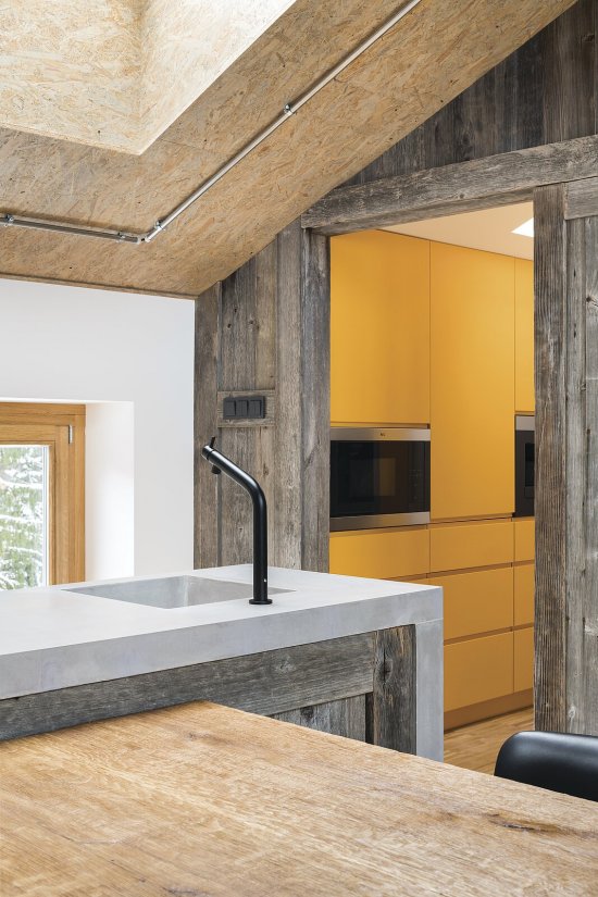 V byte II interiér dotvárajú farebné lakované povrchy, napríklad kuchynská nábytková zostava v odtieni horčicovo žltej.